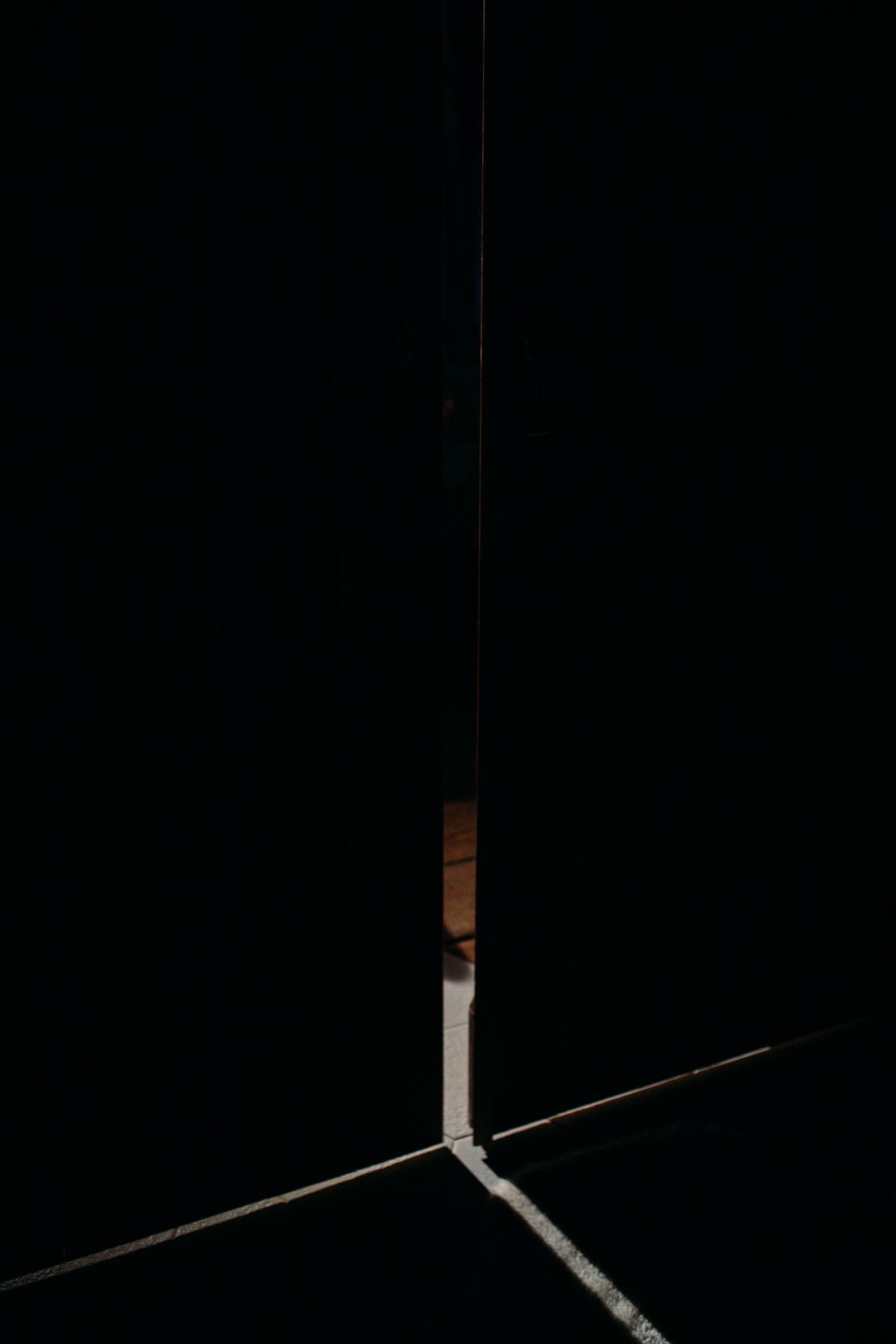 A door left ajar in a dark room with light spilling through the gap